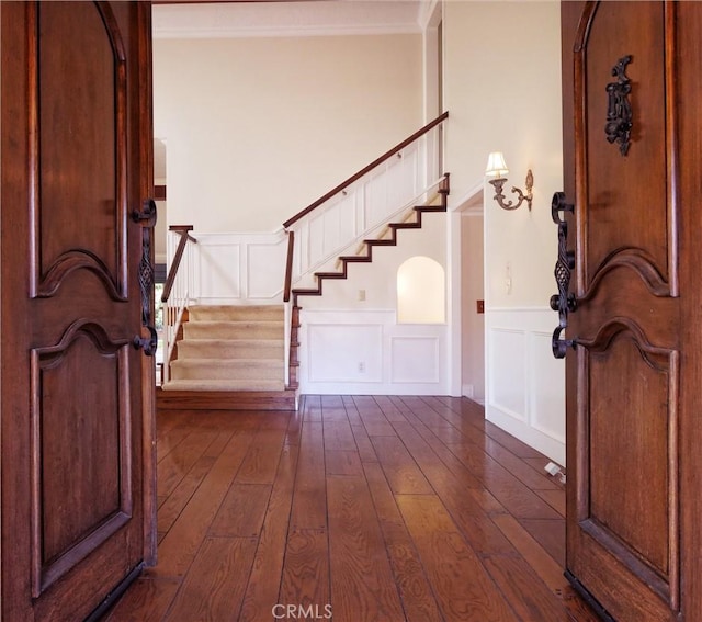 entryway with dark wood-type flooring, a decorative wall, and stairway