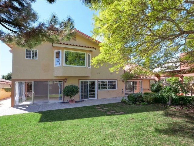 rear view of house with a yard and stucco siding