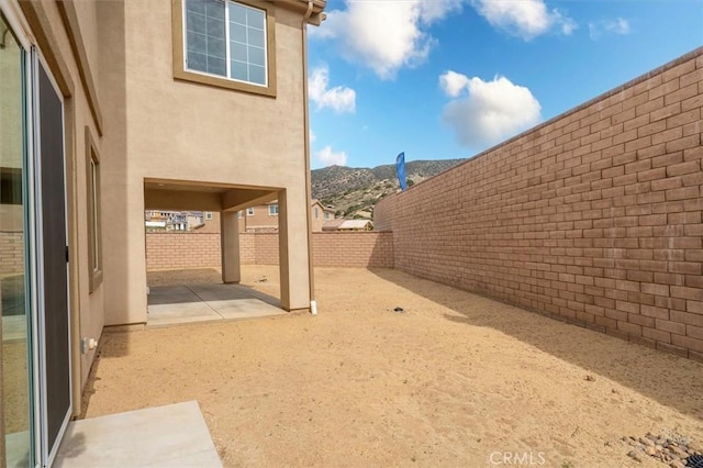 view of yard with a patio, a fenced backyard, and a mountain view