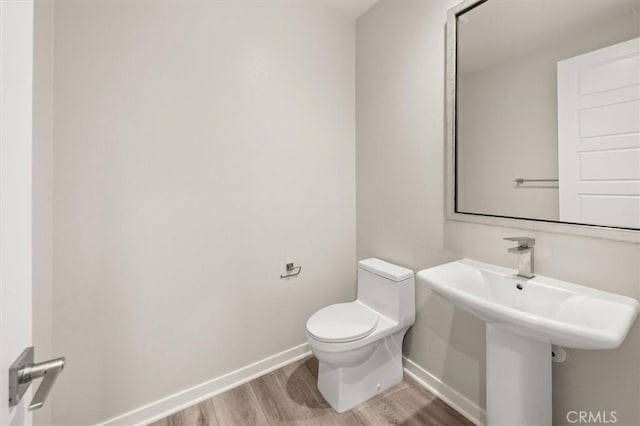 bathroom featuring baseboards, a sink, toilet, and wood finished floors