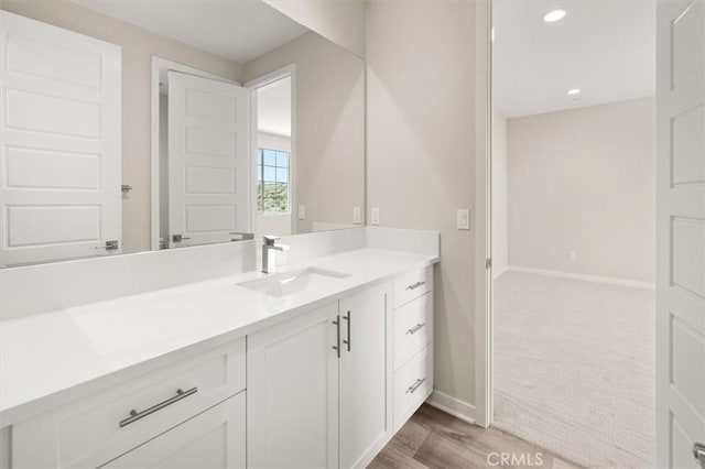 bathroom featuring recessed lighting, vanity, baseboards, and wood finished floors