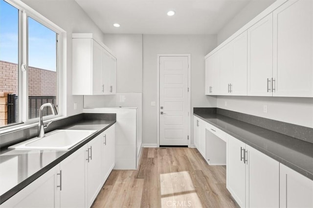 kitchen with dark countertops, a sink, and white cabinetry