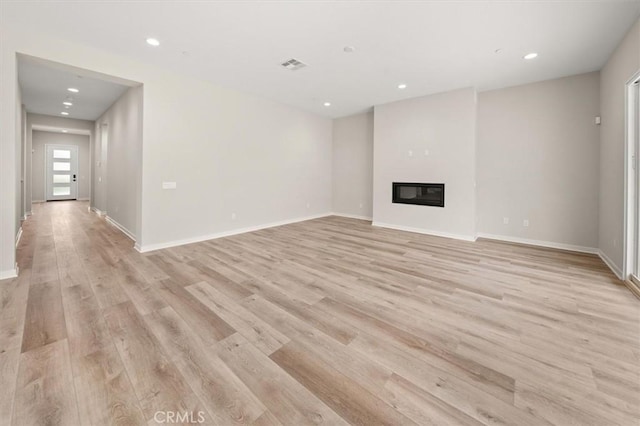 unfurnished living room with light wood-style floors, recessed lighting, visible vents, and a glass covered fireplace