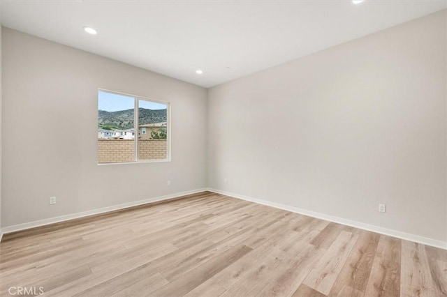 empty room with light wood-type flooring, baseboards, and recessed lighting