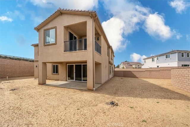 back of house featuring a patio, a fenced backyard, a balcony, a tile roof, and stucco siding