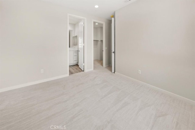 unfurnished bedroom featuring recessed lighting, light carpet, a spacious closet, and baseboards