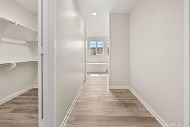 hall featuring recessed lighting, wood finished floors, and baseboards