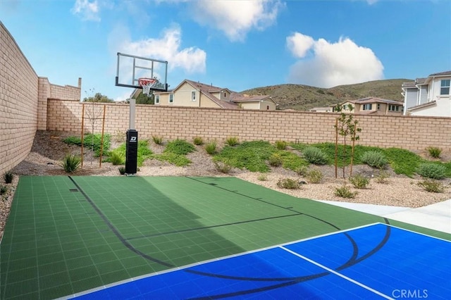 view of basketball court with a fenced backyard, a mountain view, and basketball court