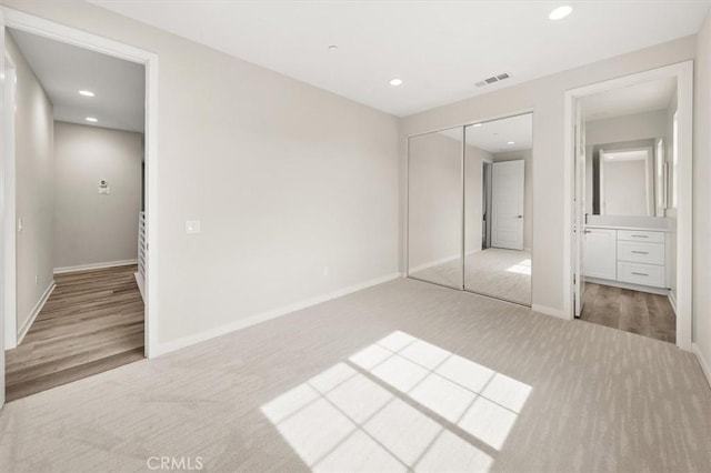 unfurnished bedroom with recessed lighting, light colored carpet, visible vents, baseboards, and a closet