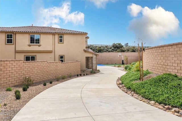 view of side of home with fence, driveway, and stucco siding