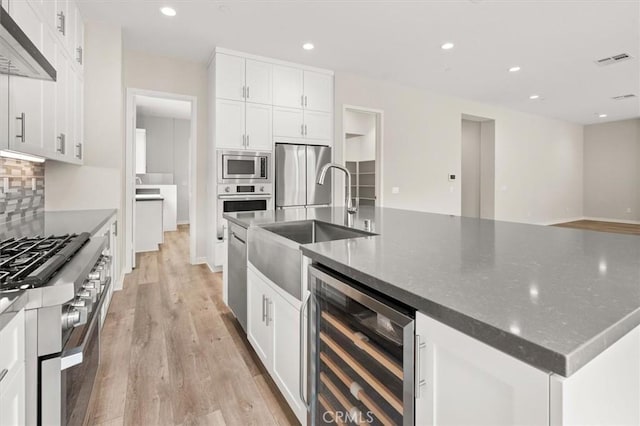 kitchen featuring tasteful backsplash, beverage cooler, visible vents, wall chimney exhaust hood, and stainless steel appliances