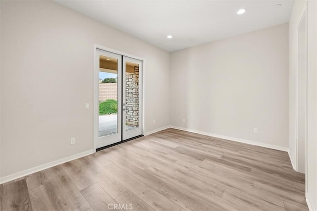 spare room featuring recessed lighting, light wood-type flooring, and baseboards