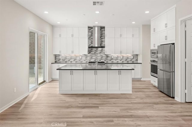 kitchen with visible vents, dark countertops, wall chimney exhaust hood, stainless steel appliances, and backsplash