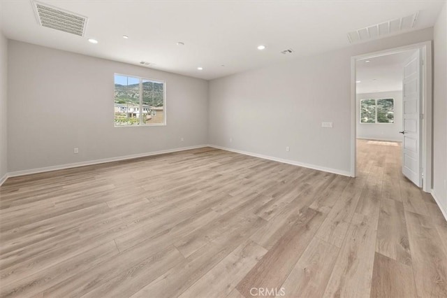 spare room featuring light wood-style floors, baseboards, visible vents, and recessed lighting