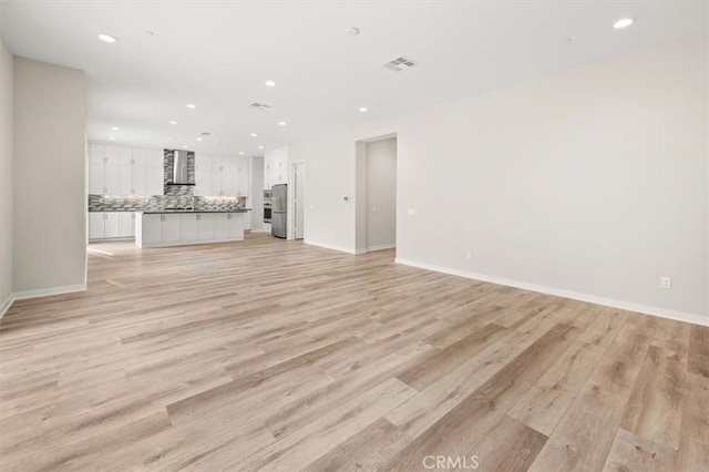 unfurnished living room with light wood-type flooring, visible vents, baseboards, and recessed lighting