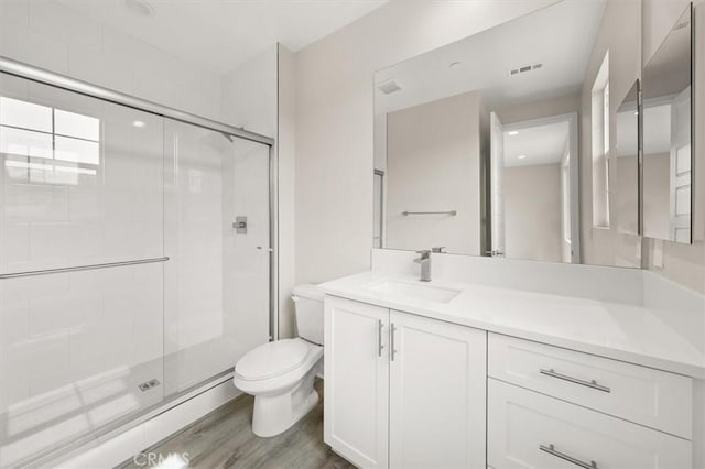 full bath with toilet, wood finished floors, vanity, visible vents, and a stall shower