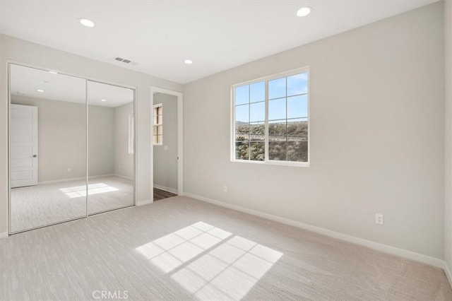 unfurnished bedroom with baseboards, visible vents, light colored carpet, a closet, and recessed lighting