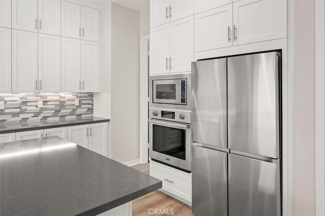 kitchen featuring stainless steel appliances, white cabinets, and decorative backsplash