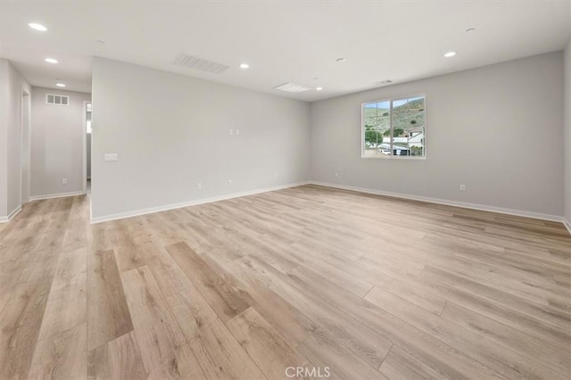 empty room with baseboards, light wood-style flooring, visible vents, and recessed lighting