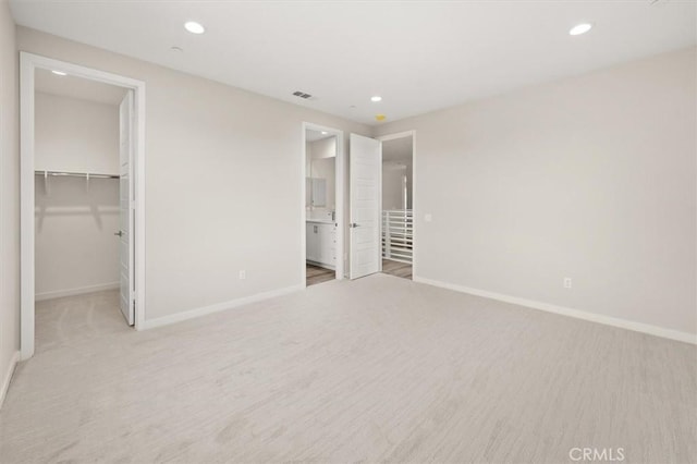 unfurnished bedroom featuring a walk in closet, visible vents, baseboards, and recessed lighting