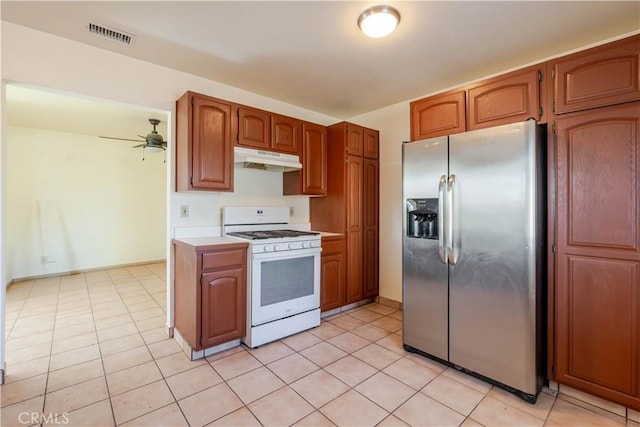 6125 Ridgeview Ave, Jurupa Valley, CA 91752 - kitchen featuring stainless steel fridge, white gas stove, under cabinet range hood, light countertops, and light tile patterned flooring