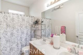 bathroom featuring double vanity, a shower with shower curtain, a sink, and toilet