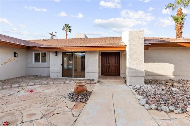 doorway to property with a tiled roof and stucco siding