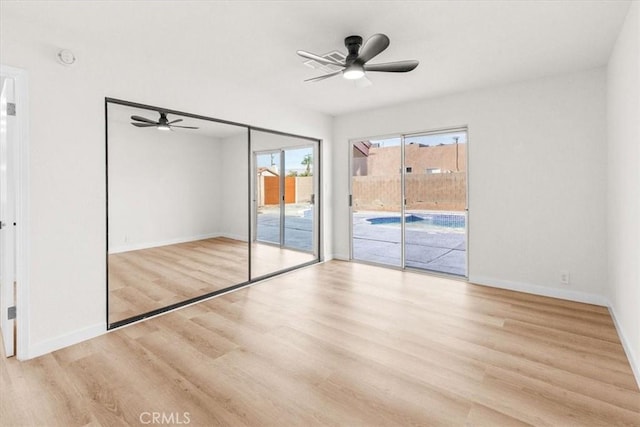 unfurnished bedroom featuring access to outside, wood finished floors, a ceiling fan, and baseboards