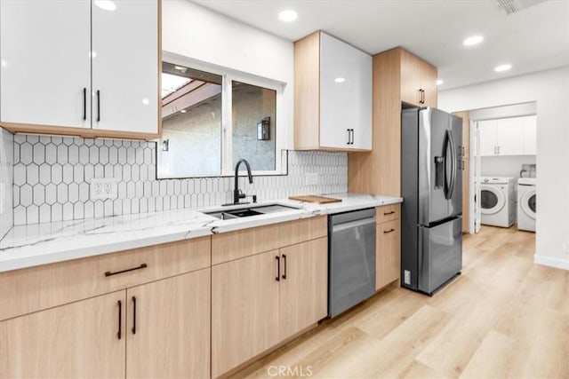 3190 E Vincentia Rd, Palm Springs, CA 92262 - kitchen with stainless steel appliances, a sink, washing machine and dryer, light brown cabinetry, and light wood finished floors