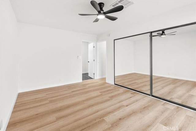 unfurnished bedroom with a ceiling fan, a closet, visible vents, and wood finished floors