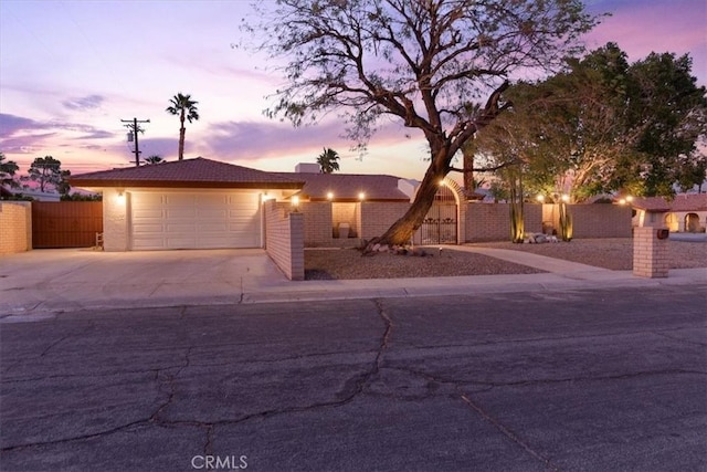 view of front facade featuring an attached garage, fence, and concrete driveway