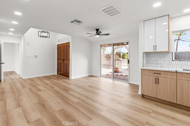 unfurnished living room with ceiling fan, light wood-style flooring, visible vents, and baseboards