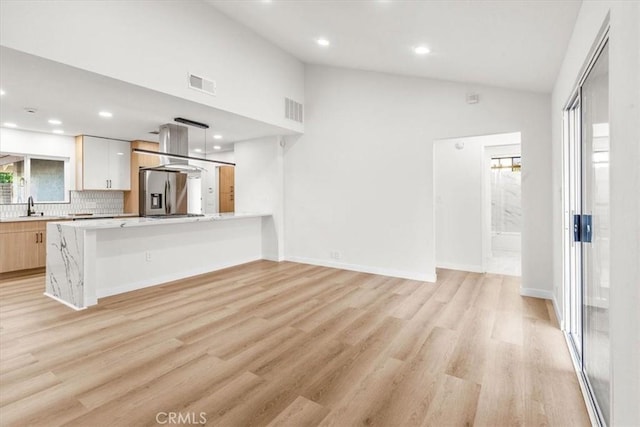 kitchen featuring light wood-style flooring, visible vents, stainless steel fridge with ice dispenser, light countertops, and decorative backsplash