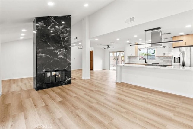 living area with a premium fireplace, recessed lighting, visible vents, and light wood-style floors