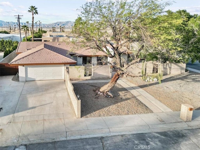 view of front of property featuring concrete driveway, a tiled roof, an attached garage, a gate, and fence