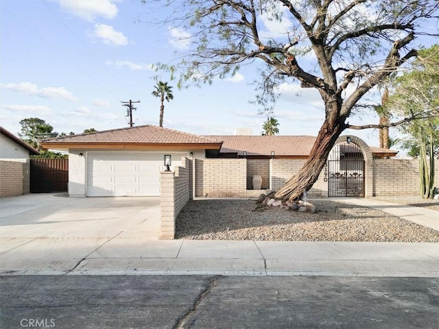 view of front of home featuring driveway, a gate, fence, and a tiled roof