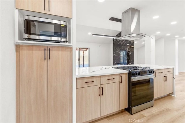 kitchen with light brown cabinets, stainless steel microwave, range with gas cooktop, and island range hood