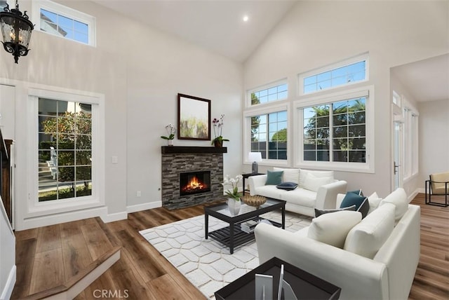 living room with baseboards, a fireplace, high vaulted ceiling, and wood finished floors