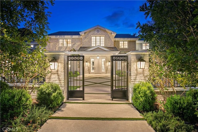 exterior space with stone siding and a gate