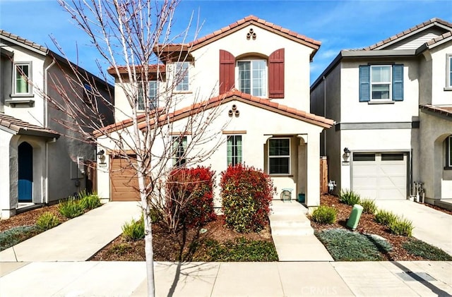 mediterranean / spanish-style house featuring driveway, a tile roof, a garage, and stucco siding