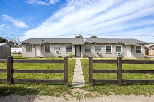 ranch-style home featuring a front lawn, a fenced front yard, cooling unit, and stucco siding