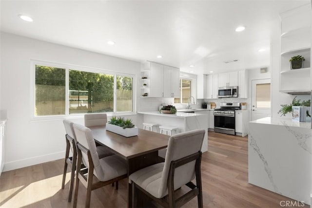 dining room featuring baseboards, recessed lighting, and light wood-style floors