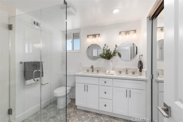 full bathroom with double vanity, a shower stall, visible vents, and a sink