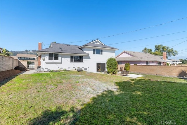 back of property with a lawn, fence, and stucco siding