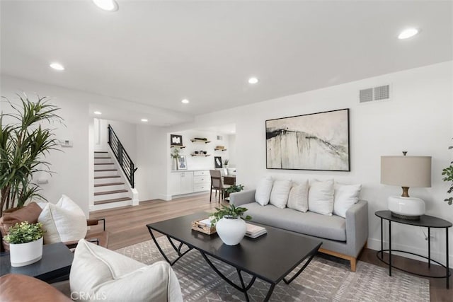 living room featuring stairs, light wood-style flooring, visible vents, and recessed lighting