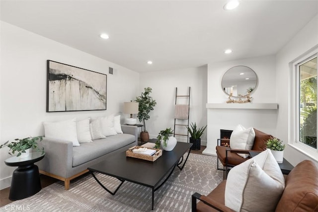 living area with a lit fireplace, visible vents, wood finished floors, and recessed lighting