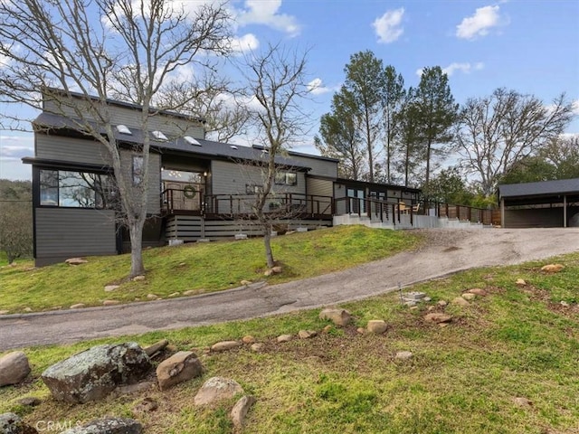 view of front of property with a deck, driveway, and a front lawn