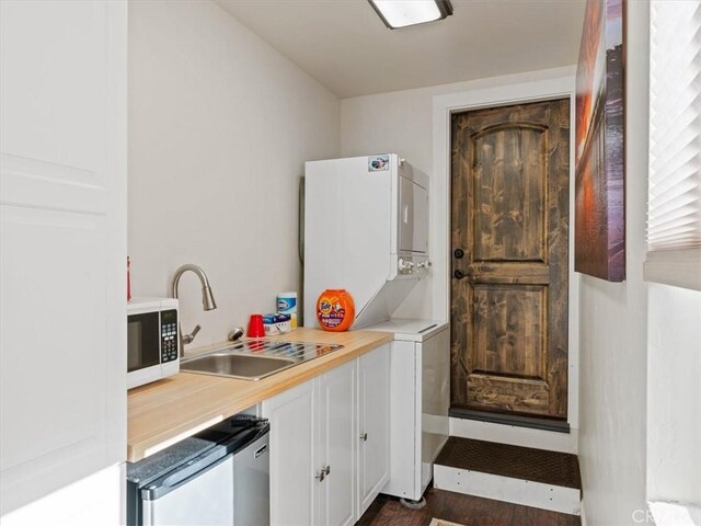 8160 Los Osos Rd, Atascadero, CA 93422 - kitchen featuring stacked washer and clothes dryer, white cabinets, light countertops, a sink, and white microwave