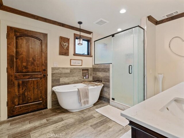 8160 Los Osos Rd, Atascadero, CA 93422 - full bathroom with wood finished floors, tile walls, crown molding, a freestanding tub, and a stall shower