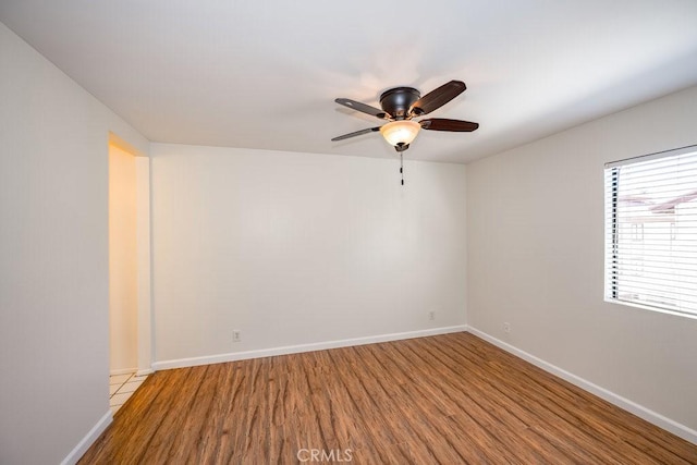 empty room featuring ceiling fan, wood finished floors, and baseboards